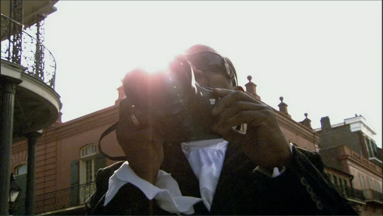 Dark Light: The Art of Blind Photographers (2009) movie still: medium — A man in a blazer stands before an ornate historic brick building exterior.…