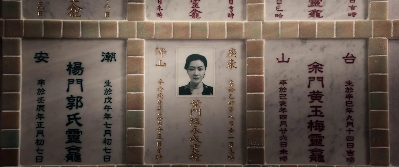 Ip Man 4: The Finale (2019) movie still: closeup — A marble columbarium wall features multiple niches with engraved Chinese characters. The central…