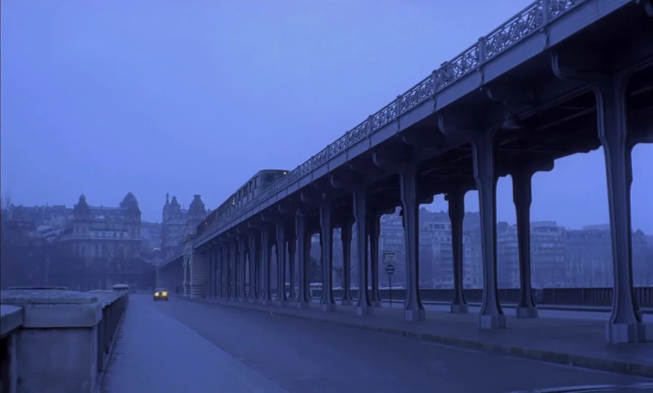 The Conformist (1970) movie still: establishing — A stone and iron viaduct extends across a city street during the blue hour. A single car with…