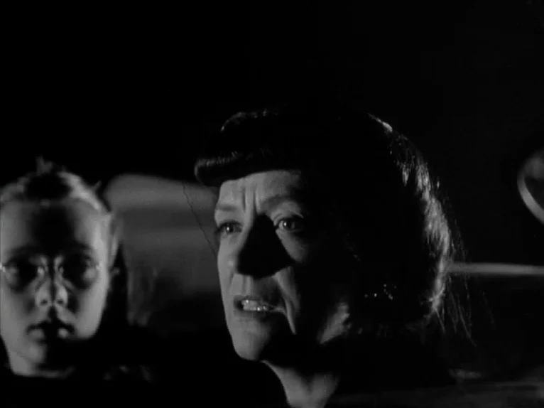 Shadow of a Doubt (1943) movie still: medium — A dark car interior at night holds a woman and a young girl. The woman sits in the driver seat…