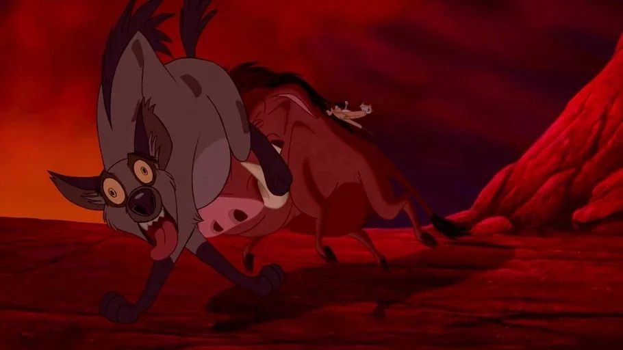 The Lion King (1994) movie still: medium — A desolate, rocky terrain bathed in a deep red glow under a dark sky. A hyena runs in terror as a warthog…