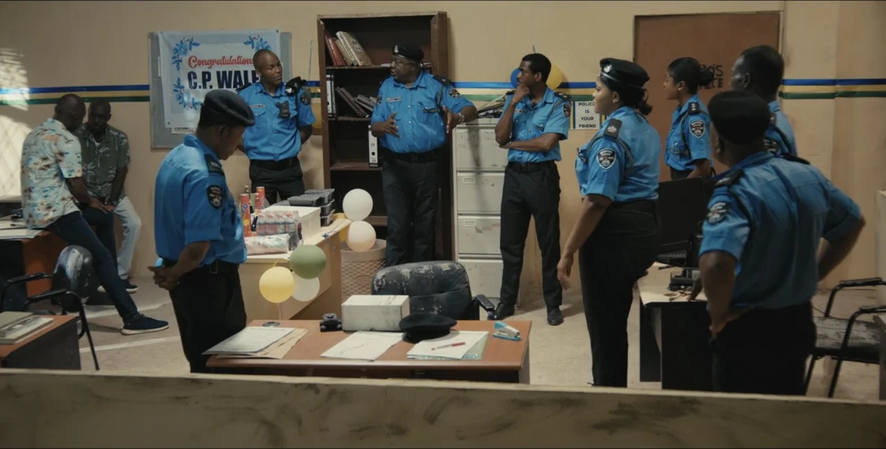 Project Assault (2025) movie still: medium — A modest police administrative office contains multiple desks, a bookshelf, and decorative balloons.…