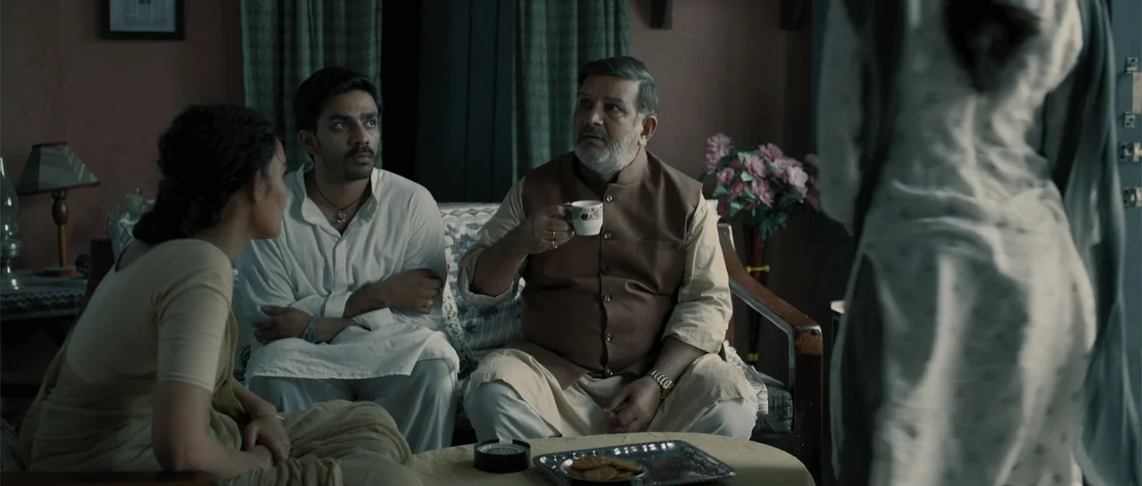 Nishaanchi 2 (2025) movie still: medium — A living room interior featuring traditional furniture and soft interior decor. Three adults sit together…