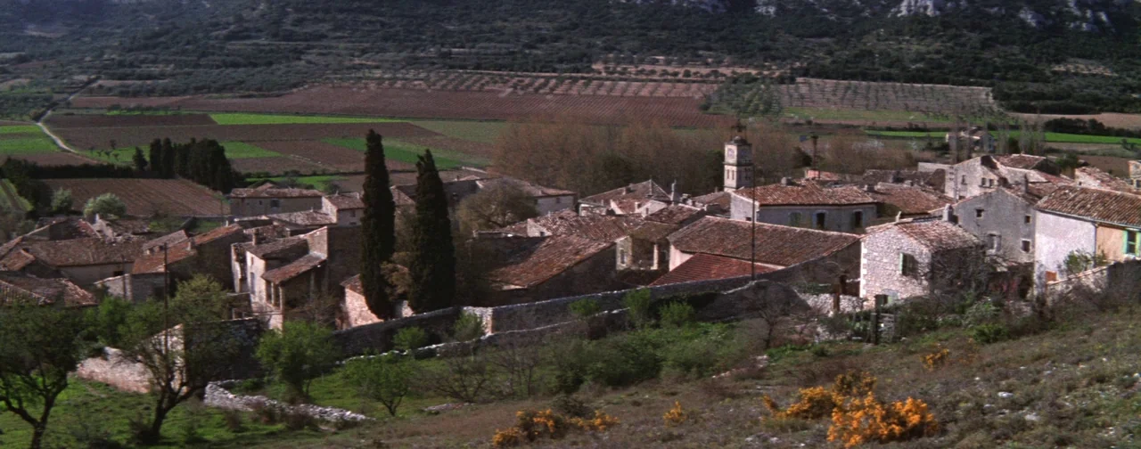 Lust For Life (1956) movie still: establishing — A rural stone village with terracotta tile roofs nestled in a hilly landscape. Agricultural fields…