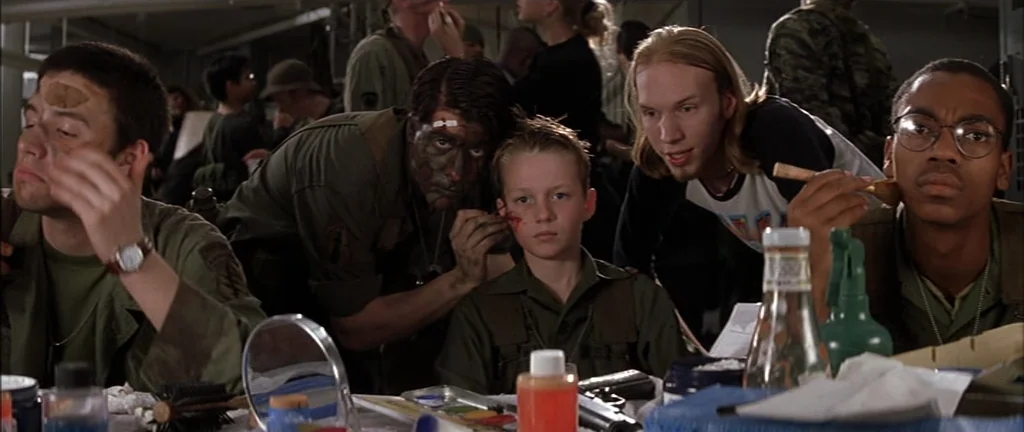 Rushmore (1998) movie still: medium — A crowded military quarters contains various men preparing themselves with paint and tools. Several soldiers…