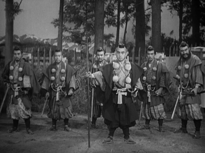 The Men Who Tread on the Tigers Tail (1945) movie still: fullbody — A group of six armed samurai stand in a clearing in front of trees. They face…