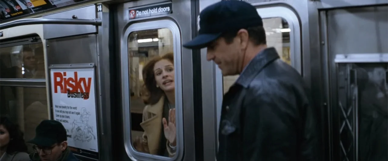 Conspiracy Theory (1997) movie still: medium — An interior of a subway car features metal doors and advertising posters on walls. A man stands in…
