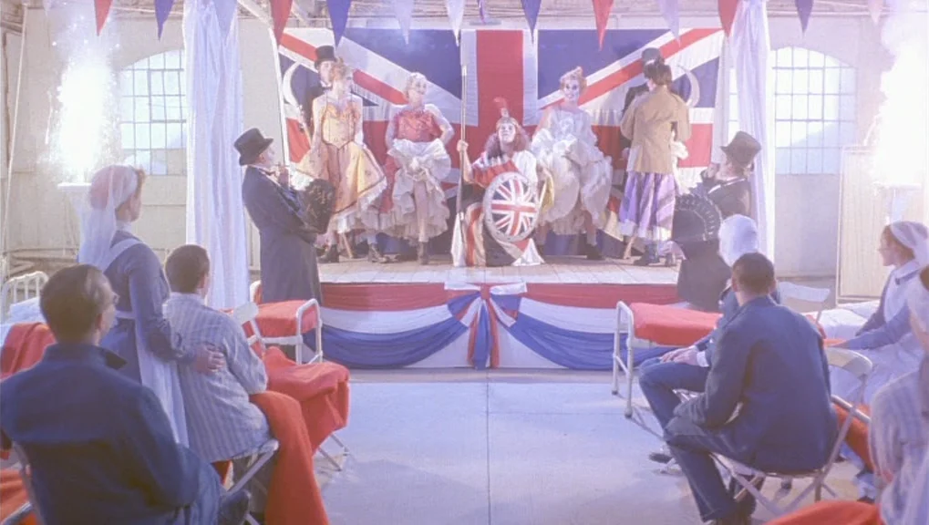 War Requiem (1989) movie still: wide — A hospital ward decorated with Union Jack bunting hosts a theatrical stage performance. Patients and nurses…
