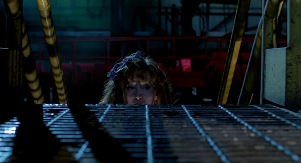 A Nightmare On Elm Street 2: Freddy’s Revenge (1985) movie still: closeup — A dimly lit industrial environment features a dark metal catwalk with…