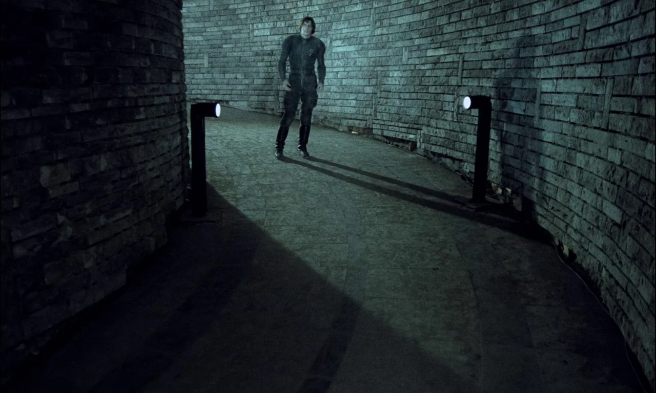 On The Silver Globe (1988) movie still: fullbody — A curved corridor features walls made of rough-cut stacked stone bricks. A lone man stands in the…