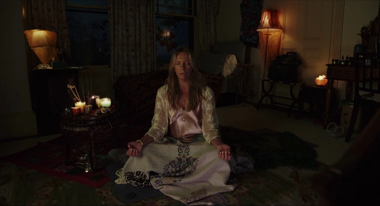Knives Out (2019) movie still: medium — A dimly lit room contains various candles and soft lamps scattered around the space. A middle-aged woman…