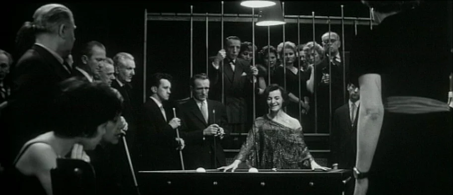 And The Fifth Horseman is Fear (1965) movie still: wide — A dark, formal setting features people standing behind vertical metal bars observing a…