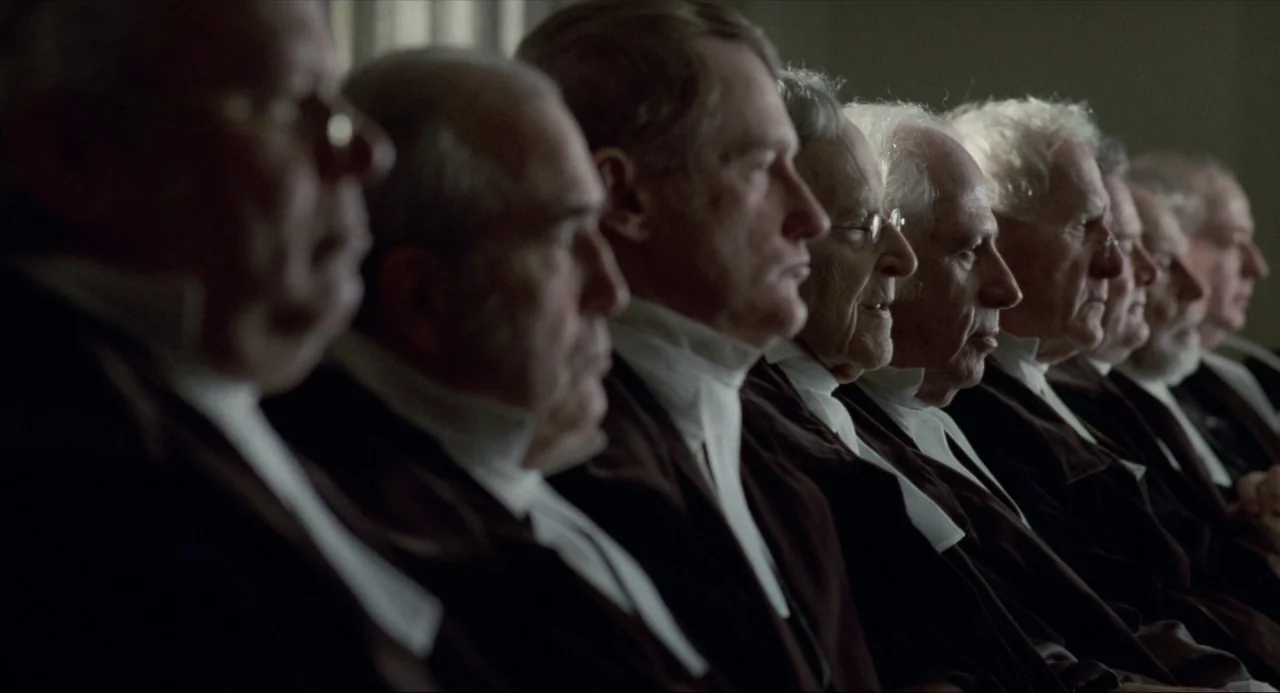 Amistad (1997) movie still: medium — A row of judges in traditional black robes sits in a formal legal setting. The men are positioned in profile…