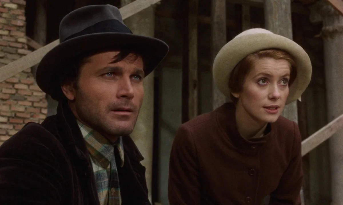 Tristana (1970) movie still: medium — A construction site features unfinished wooden scaffolding and a rough brick wall background. A man in a…