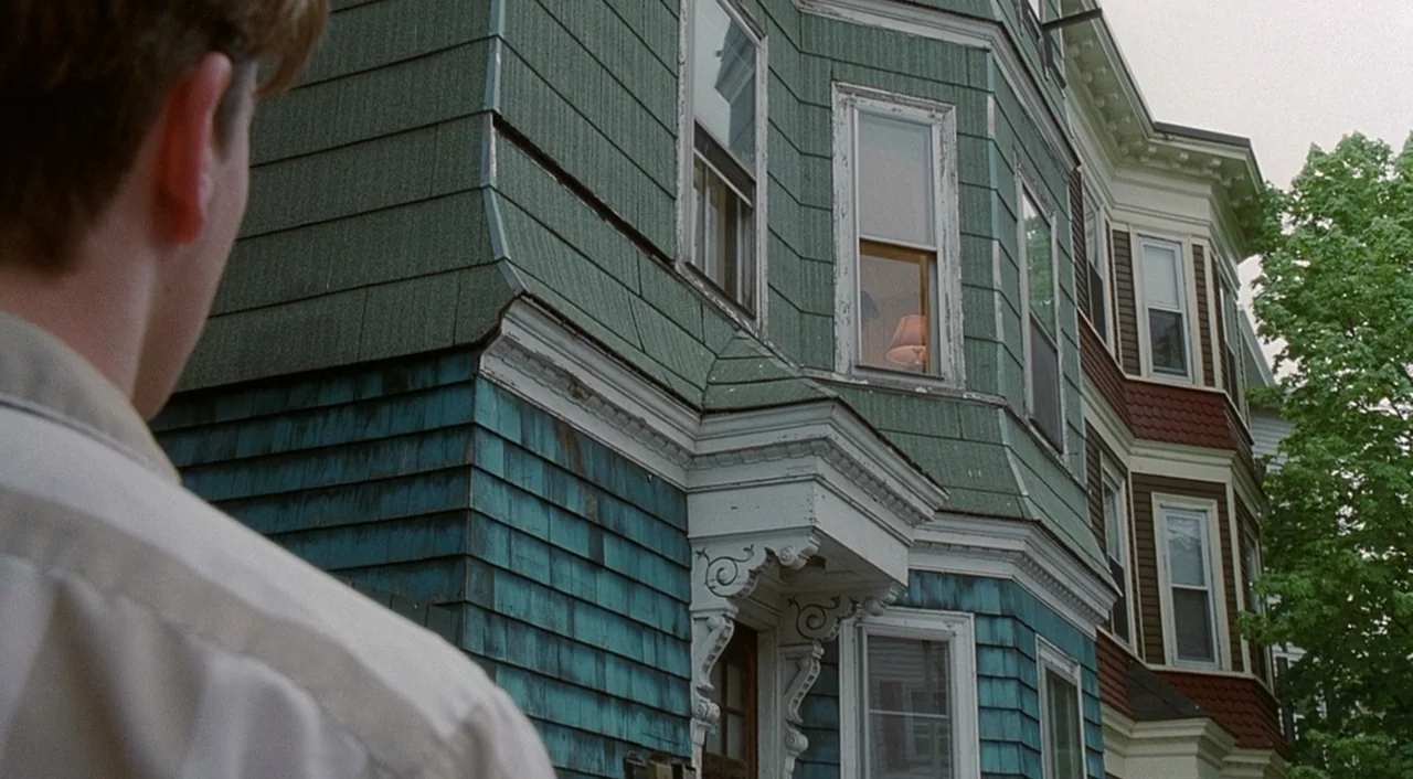 Good Will Hunting (1997) movie still: medium — A teal-shingled multi-story suburban building stands under a bright, overcast daylight sky. A man…