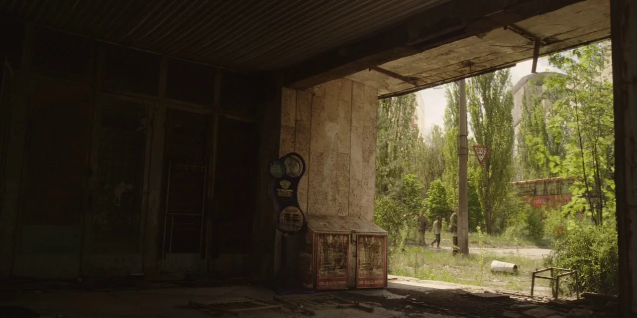 The Girl With All The Gifts (2016) movie still: wide — A dark, dilapidated interior looks out onto an overgrown, foliage-filled outdoor area. A…