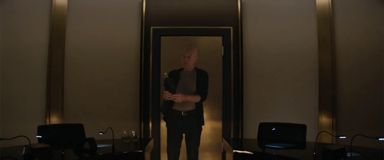 Charlie's Angels (2019) movie still: fullbody — A dimly lit room features a central doorway framed by dark panels and gold trim. An elderly man…