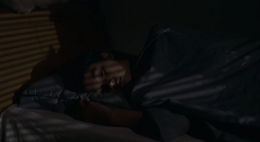 Yi-Yi (A One and A Two) (2000) movie still: closeup — A dimly lit room at night features a child resting in a bed. Light from window blinds creates…