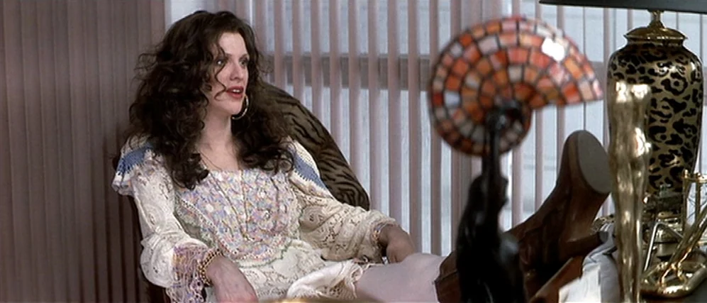The People vs. Larry Flint (1996) movie still: medium — A workspace with vertical window blinds and ornate desk ornaments. A woman sits in a chair…
