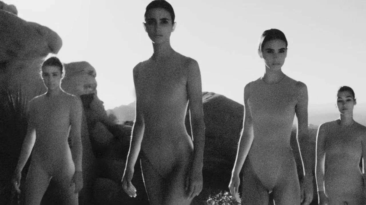 Divinity (2023) movie still: fullbody — A high-contrast black and white shot shows four women standing in a rocky desert. They are arranged in a…