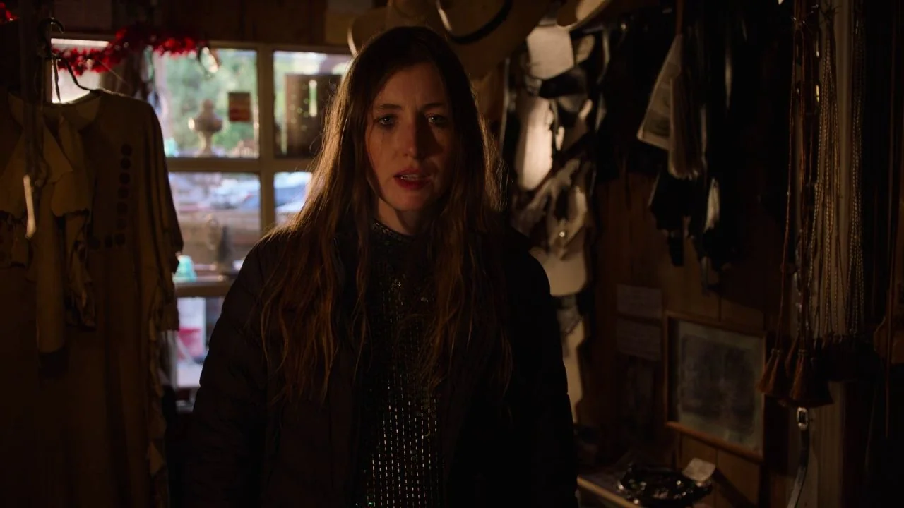 She Dies Tomorrow (2020) movie still: medium — A cluttered retail shop interior with wooden walls and various hanging merchandise items. A woman…