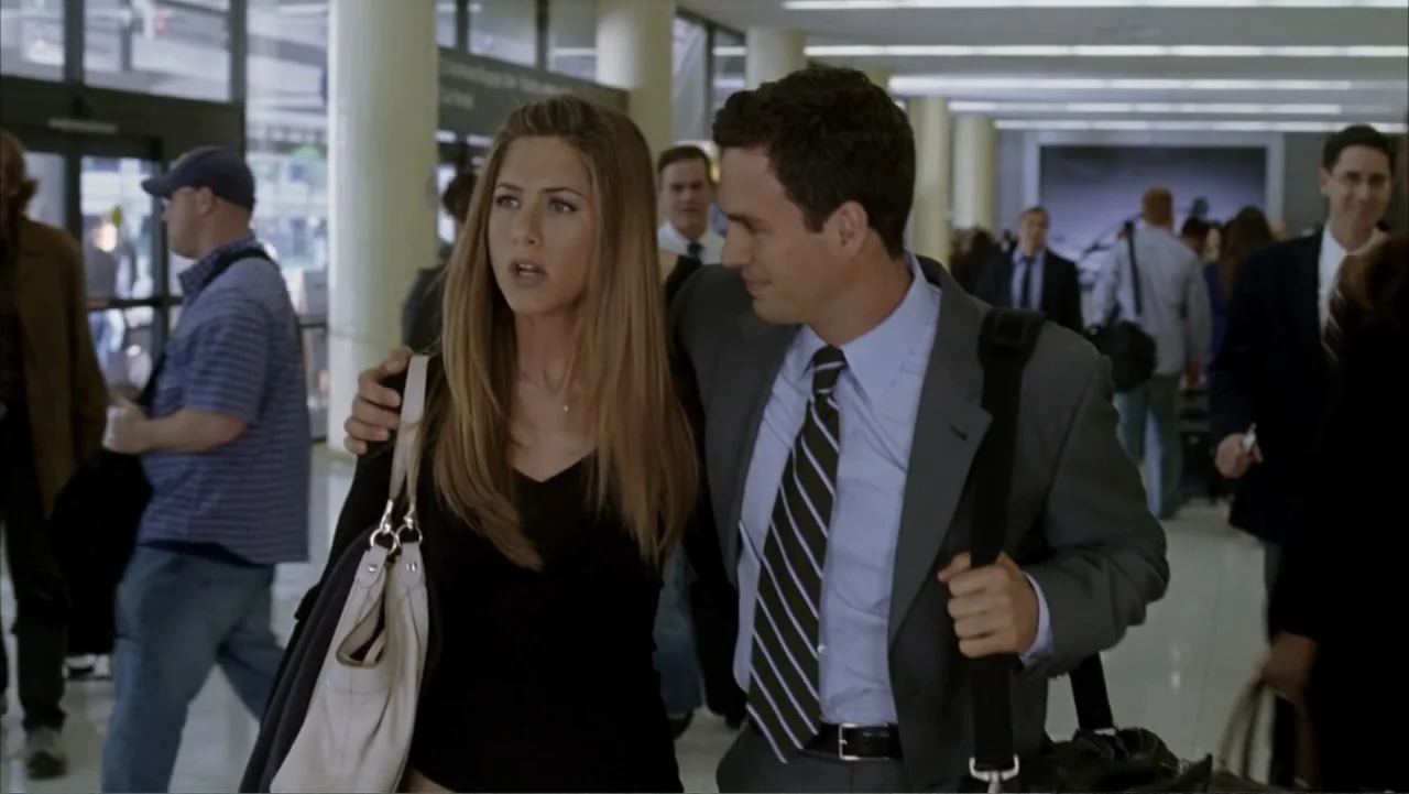 Rumor Has It... (2005) movie still: medium — An airport terminal with bright lighting and people walking in the background. A man walks with a woman…