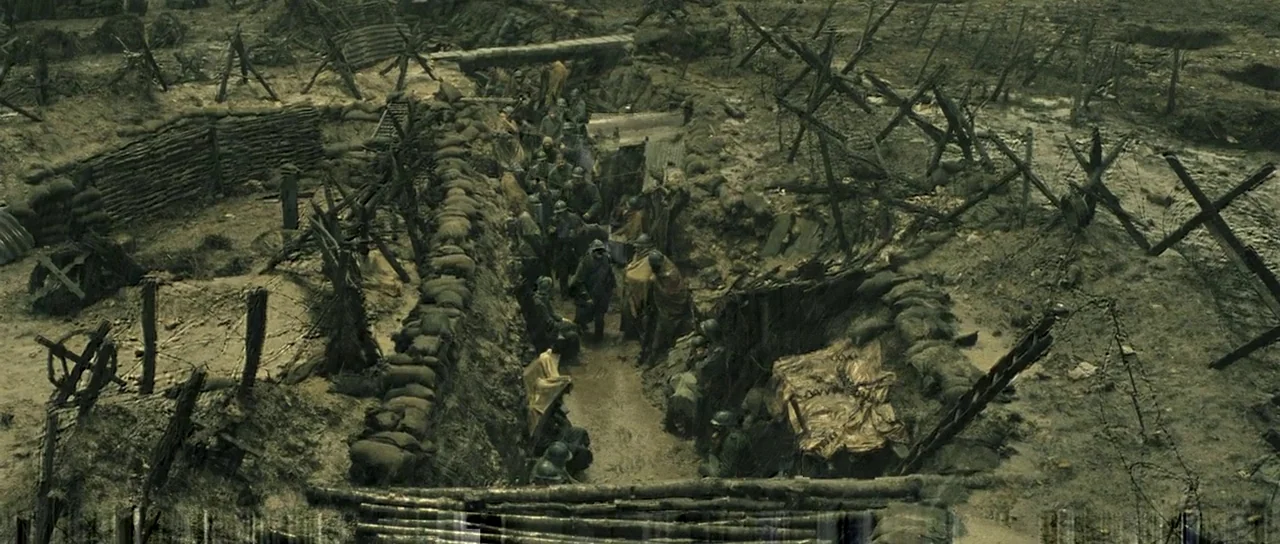 A Very Long Engagement (2004) movie still: wide — A muddy, fortified trench system cuts through a barren, war-torn landscape. Soldiers walk slowly…