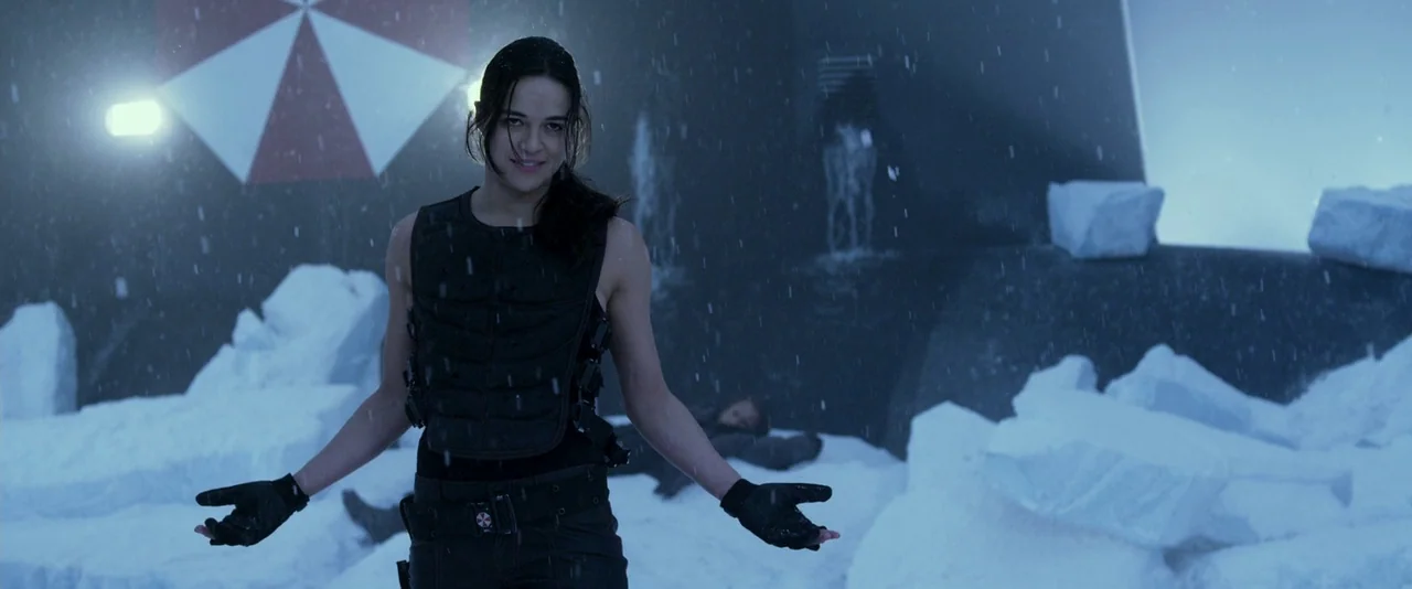 Resident Evil: Retribution (2012) movie still: medium — A woman stands in a snowy environment in front of a dark wall with a red and white umbrella…