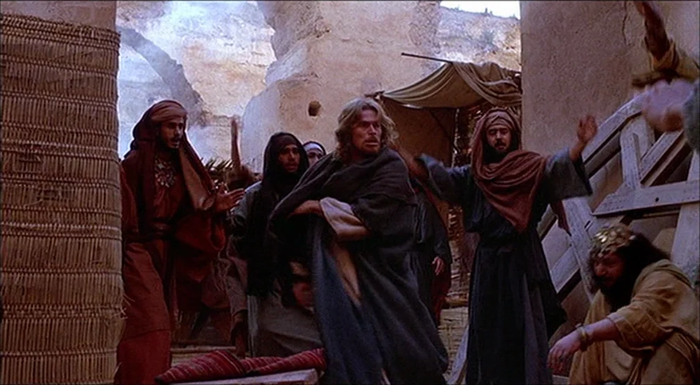 The Last Temptation Of Christ (1988) movie still: fullbody — An arid, dusty stone passageway with textured mud-brick walls and wooden scaffolding.…
