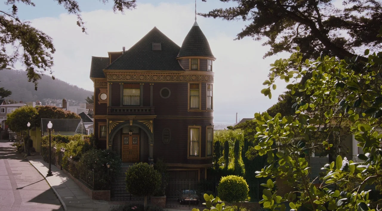 Ant-Man (2015) movie still: establishing — A dark brown Victorian-style mansion stands centrally in a quiet suburban residential street. The…
