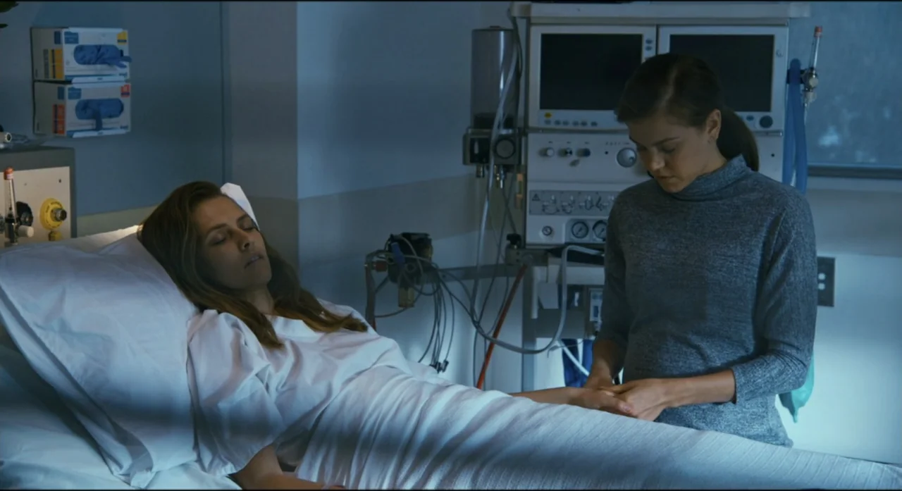 Ride Like a Girl (2019) movie still: medium — A clinical medical space features a reclining patient bed and electronic monitoring equipment. A woman…
