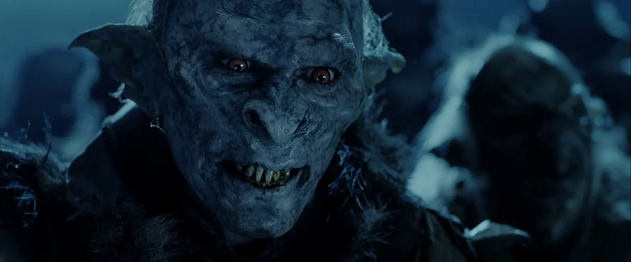 The Lord of The Rings: The Two Towers (2002) movie still: closeup — A dark, dimly lit environment with textured stone surfaces in the background. An…
