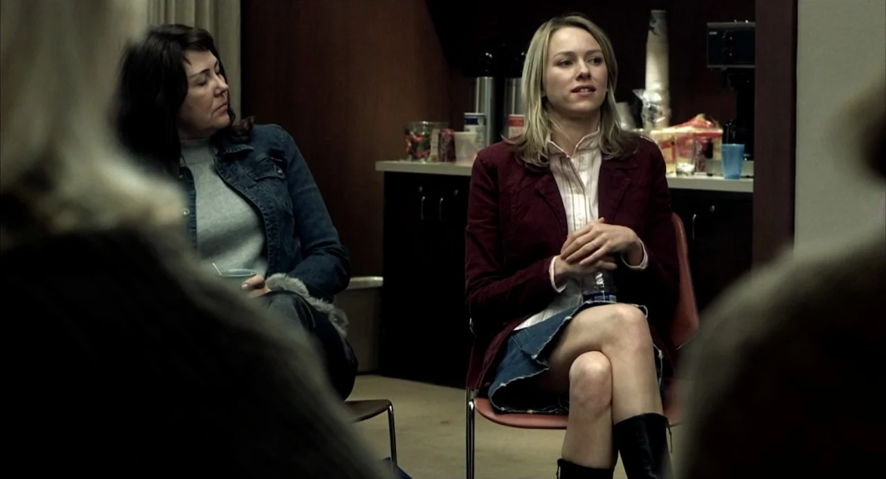 21 Grams (2003) movie still: medium — A functional meeting room features a counter with beverage supplies and folding chairs. Two women sit in the…