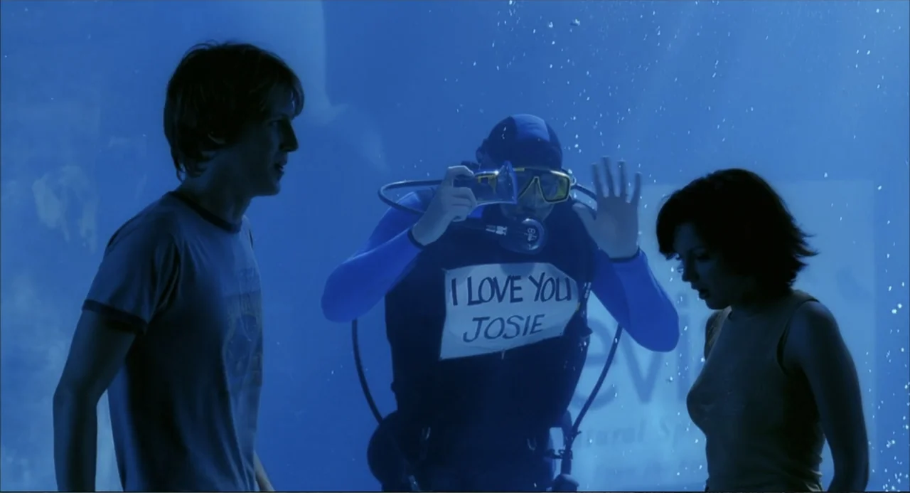 Josie and the Pussycats (2001) movie still: medium — A brightly lit aquarium display features water filled with small air bubbles. A diver behind…