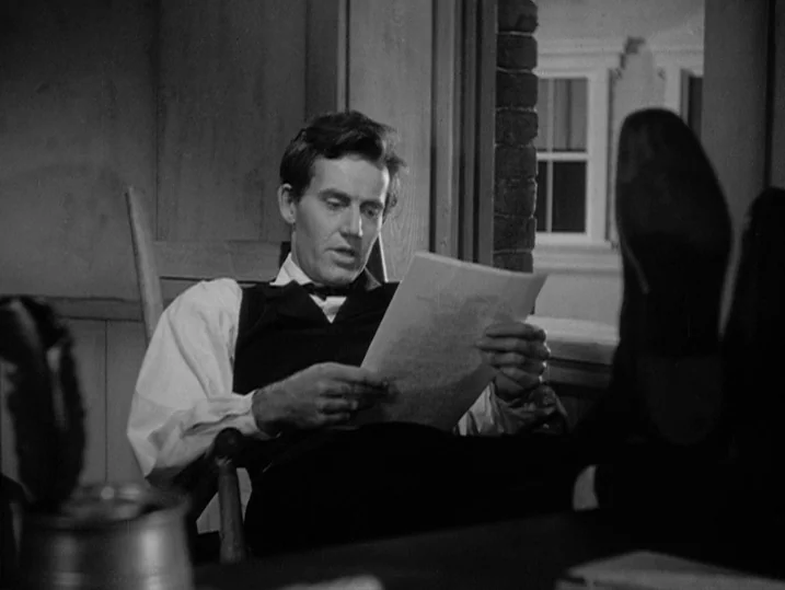 Young Mr. Lincoln (1939) movie still: medium — A 19th-century study features a wooden chair and a nearby window with paneled glass. A man sits in…