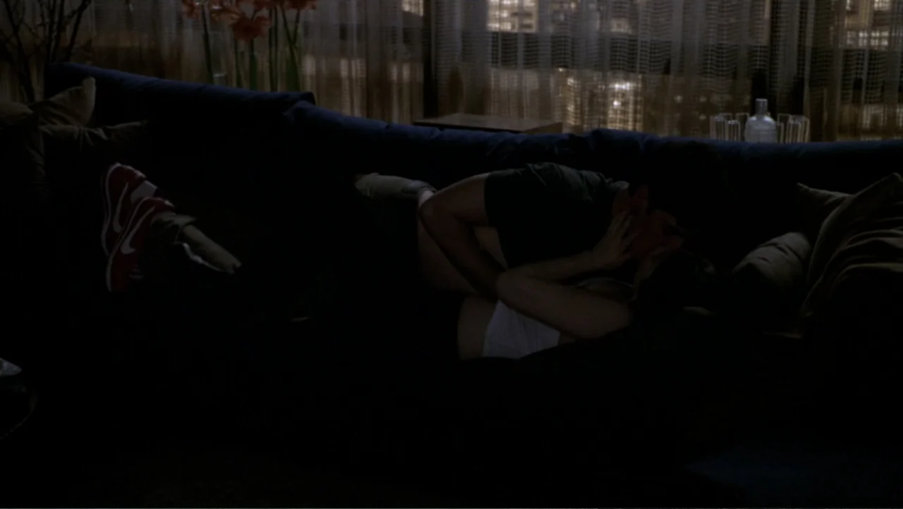 What Women Want (2000) movie still: medium — A dark, modern apartment interior features a large sofa positioned in front of windows. A man and a…