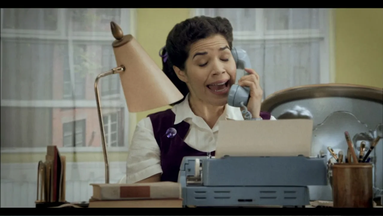 Six by Sondheim (2013) movie still: medium — An office setup from the 1950s features a typewriter on a wooden desk. A woman sits behind the desk…