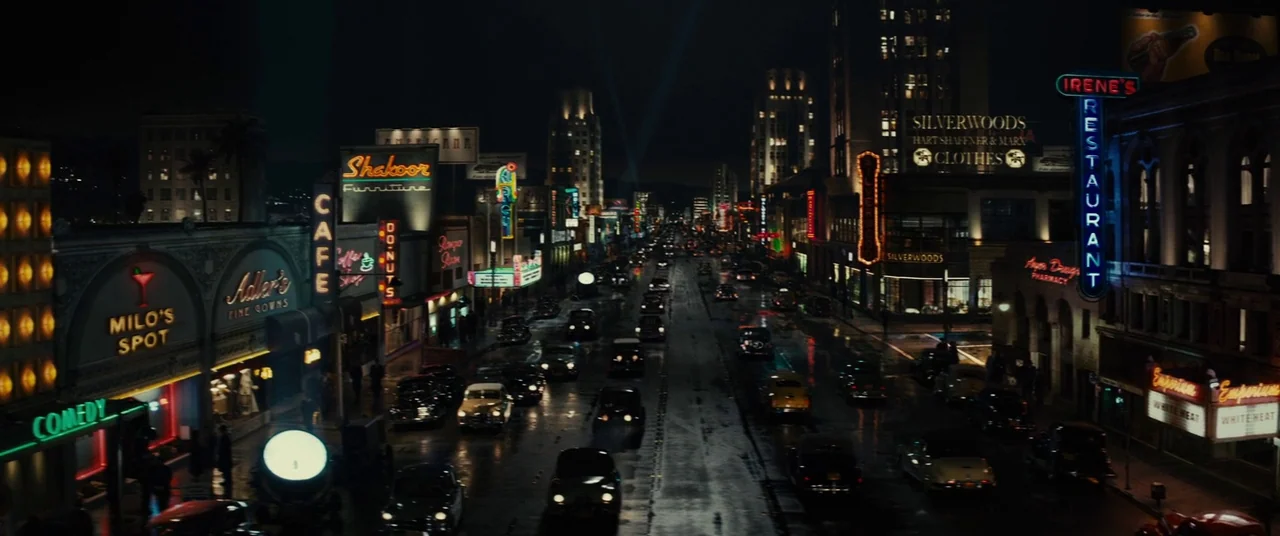 Gangster Squad (2013) movie still: establishing — A bustling city street at night is lined with multiple glowing neon signs. Numerous vintage…