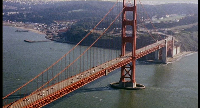 Perversion Story (1969) movie still: establishing — An aerial view shows the Golden Gate Bridge stretching across the water. Cars traverse the…