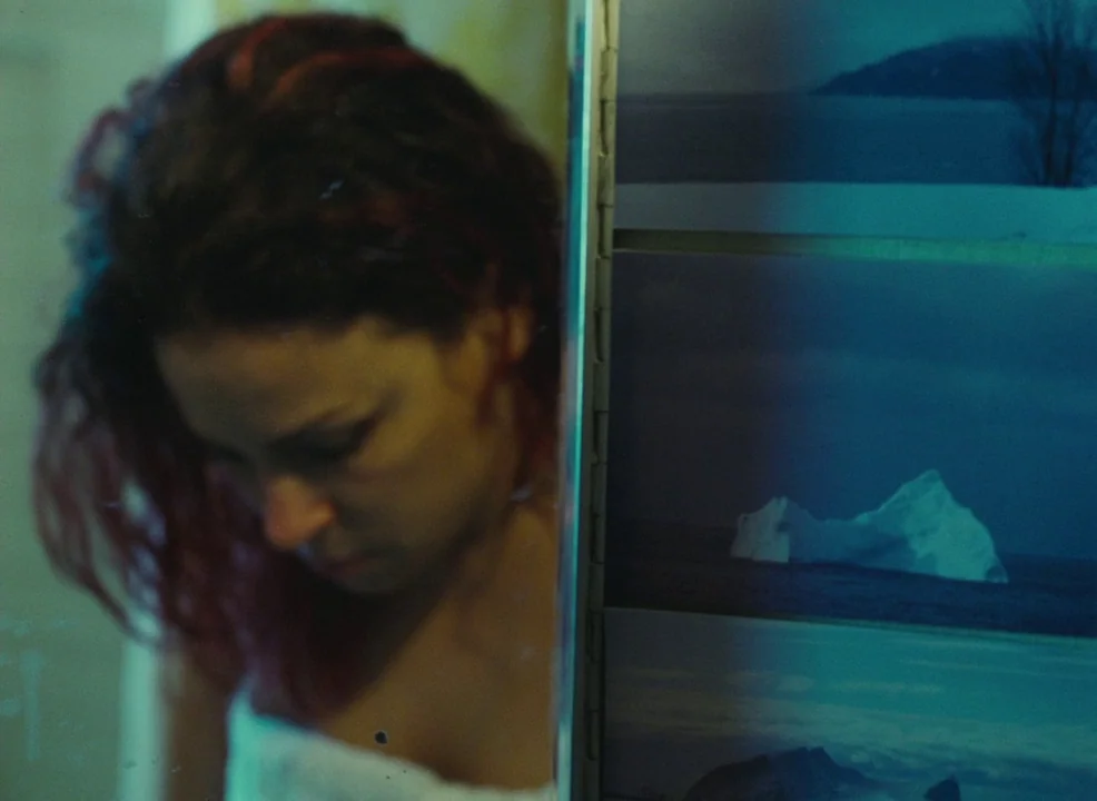 Laurence Anyways (2012) movie still: closeup — A woman stands in a dimly lit bathroom near a reflective surface. She gazes downward while wearing a…