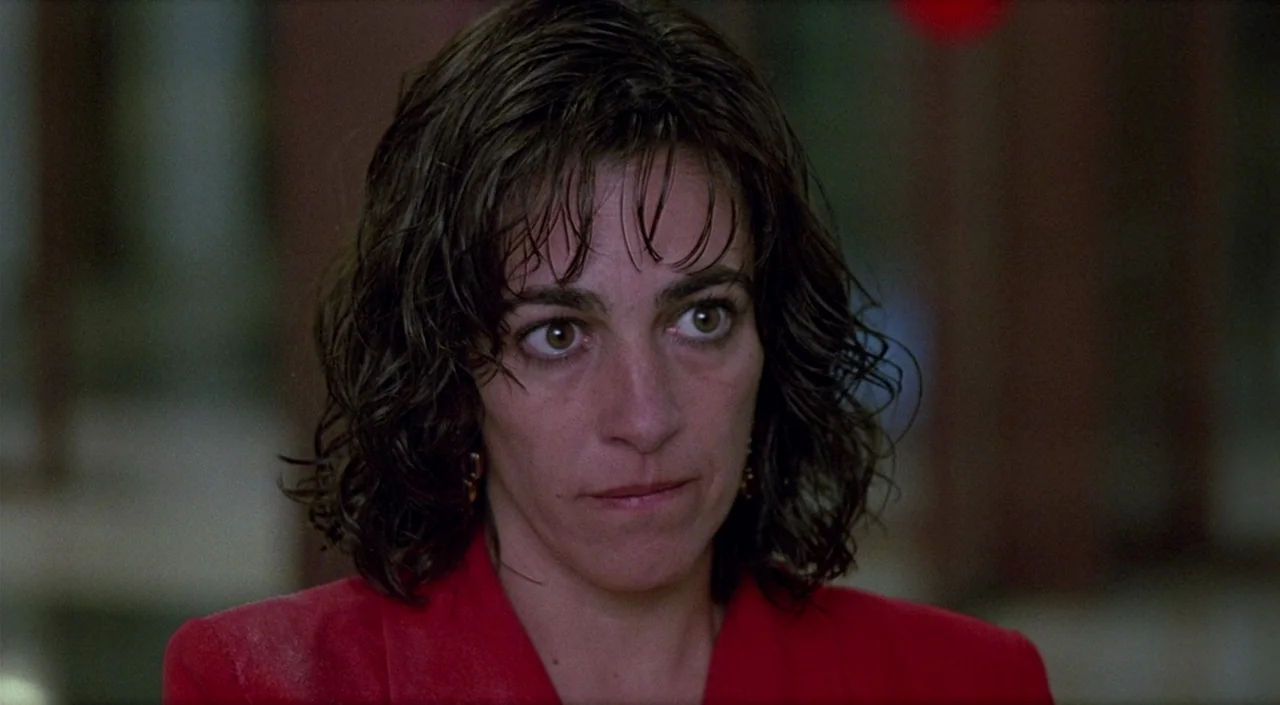 Women on the Verge of a Nervous Breakdown (1988) movie still: closeup — A woman stands in an undefined interior space with a blurred, dark backdrop.…