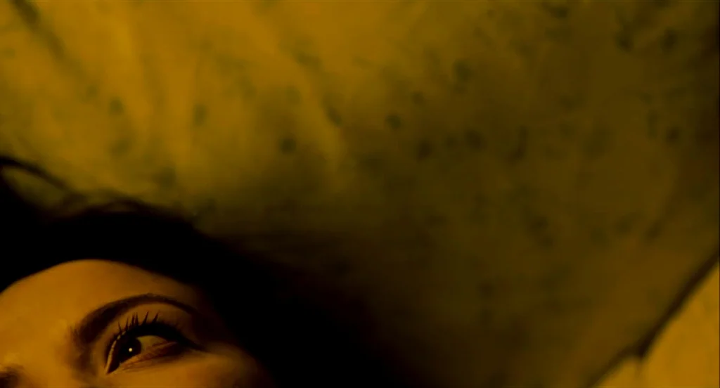 Heartbeats (Les Amours Imaginaires) (2010) movie still: closeup — A close-up view shows a person lying down on a textured yellow surface. The frame…
