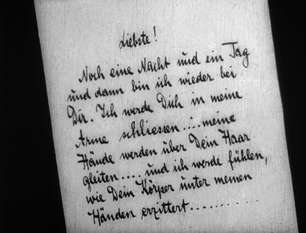 The Hands of Orlac (1924) movie still: closeup — A close-up shot displays a handwritten note on light-colored paper with dark ink. The script in…