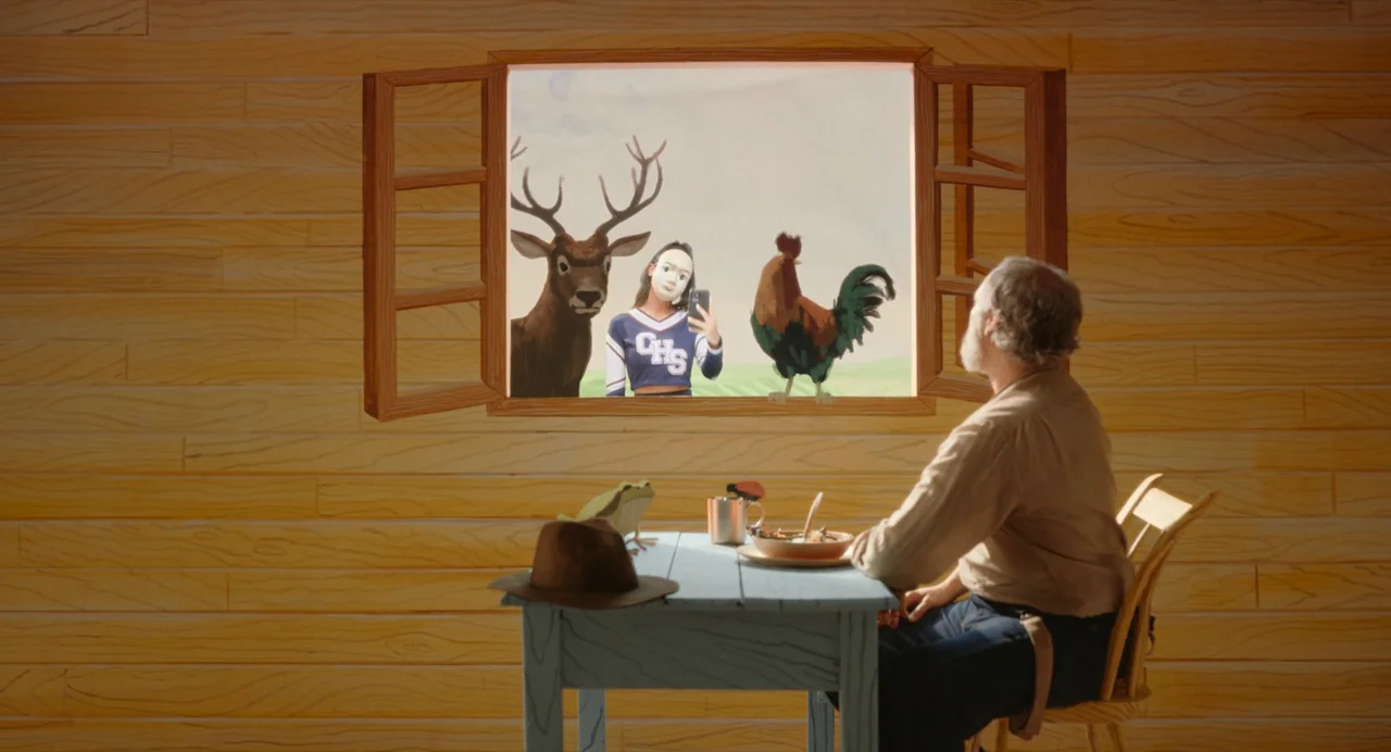 Beau Is Afraid (2023) movie still: medium — A man sits at a blue wooden table inside a room with painted wood walls. Through an open window, a girl…
