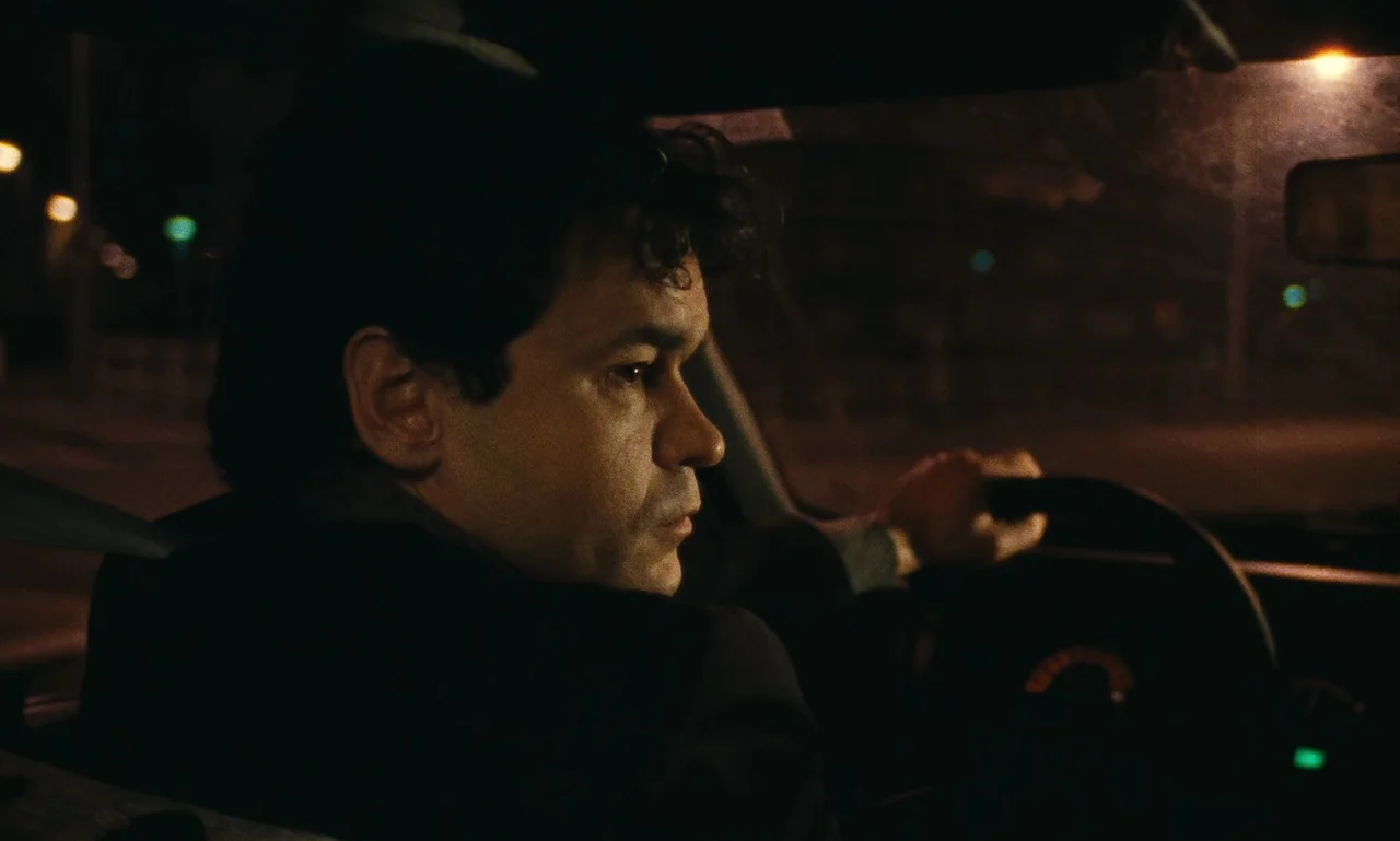 A Tale of Winter (1992) movie still: medium — A man drives a car at night on a dark road. He stares forward while gripping the steering wheel.