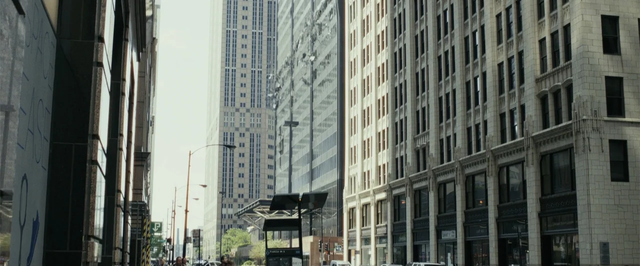 Rampage (2018) movie still: establishing — A dense urban canyon features rows of tall office buildings with stone and glass facades. Tall…