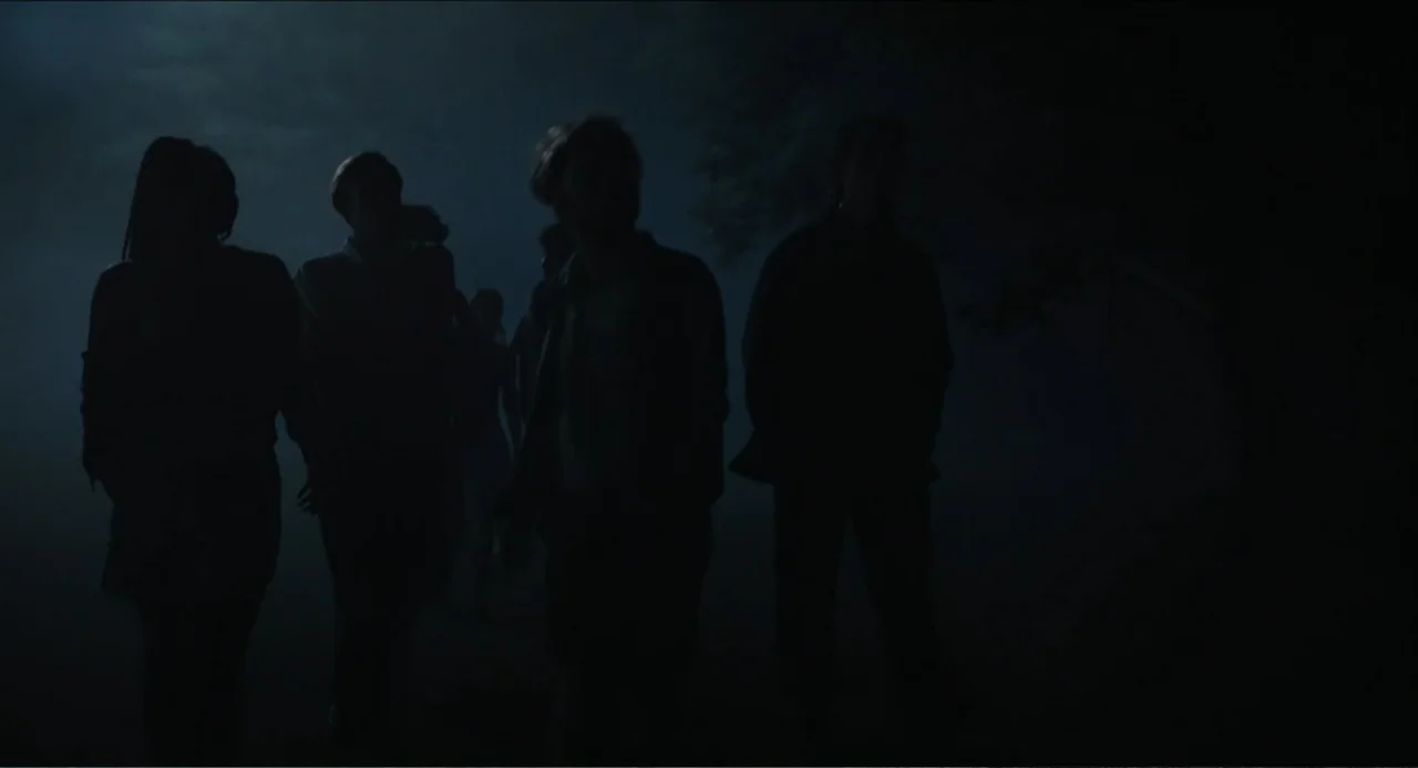 Hell of a Summer (2025) movie still: fullbody — A group of people walk through a dense foggy area at night. The subjects appear as dark silhouettes…