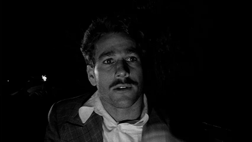 Paper Moon (1971) movie still: closeup — A man stands in a dark outdoor setting at night. He stares off-camera while light from an unseen source…