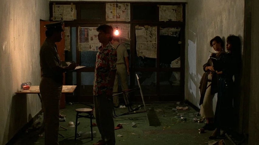The Terrorizers (1986) movie still: fullbody — A cluttered apartment interior has trash on the floor and newspaper-covered windows. A uniformed…
