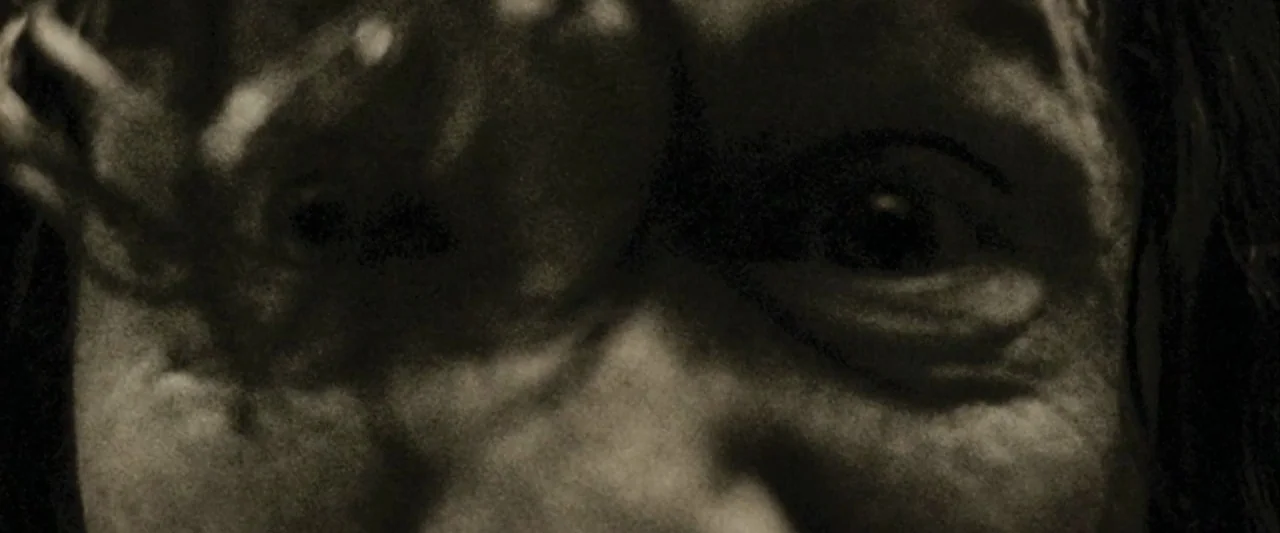 Harry Potter and the Prisoner of Azkaban (2004) movie still: closeup — A close-up of a human face emerging from deep shadow in a dark space. The…
